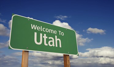 Welcome to utah green road sign over blue sky with some clouds