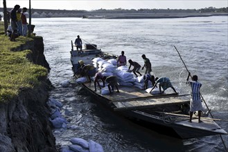 Public Works Department (PWD) of Assam labourer throwing sand bag from boat in the banks of Beki