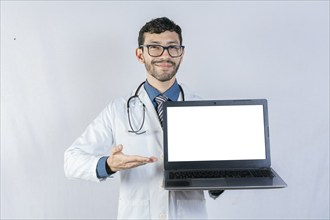 Smiling doctor showing laptop screen isolated. Handsome doctor pointing at laptop screen isolated