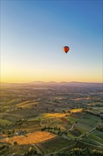 Hot air balloon drifting above undulating tuscan hills in sunsets golden light, AI generated