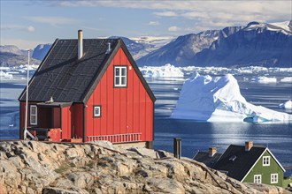 Typical Greenlandic houses in front of icebergs, Inuit settlement, summer, sunny, Uummannaq, West