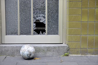 Shattered glass pane on a front door and football, Germany, Europe