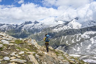 Mountaineer on a hiking trail in front of a picturesque mountain landscape, rocky mountain peaks