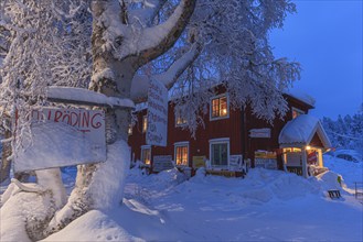 Illuminated Swedish red wooden house, shop, snow, twilight, winter, Porjus, Lapland, Sweden, Europe