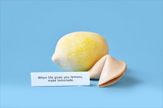 Fortune cookie with motivational text on paper saying 'When life gives you lemons, make lemonade'