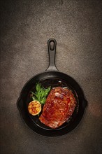 Grilled rib eye steak, in a cast-iron skillet, top view, homemade, no people