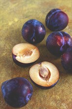 Plums scattered on the table, fresh, top view, yellow-orange background, no people