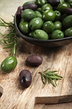 Chalkidiki olives, classic Greek green olives, in a bowl on a cutting board, top view, without