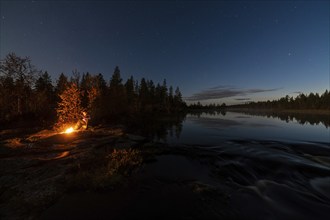 Man in the evening at a bivouac with campfire, Lapland, Sweden, Scandinavia, Europe