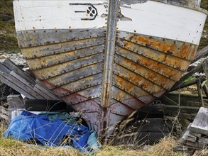 Weathered hull of derelict fishing boat on the shore of the Arctic Ocean, at the edge of the