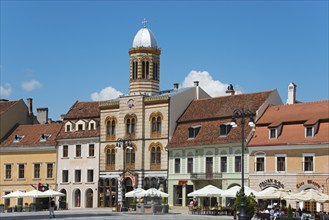 Historic city centre with colourful buildings and a café under a clear blue sky, Church of the