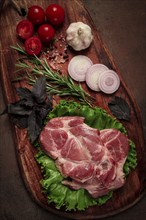 Raw pork steak, two pieces, on a wooden background