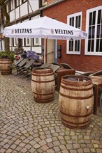 Old wine or beer barrels as decoration and a parasol with Veltins advertising in the outdoor area