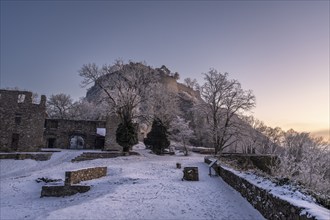 The snow-covered Karlsbastion of the Hohentwiel fortress ruins in front of sunrise on a cold winter