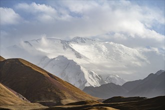 Dramatic mountain landscape, mountain valley, behind glaciated and snow-covered mountain peak Pik