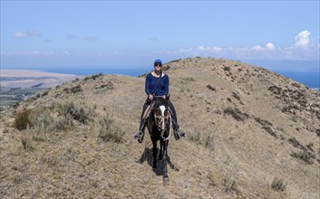 Young tourist riding in the mountains near Kysyl-Suu, Kyrgyzstan, Asia