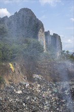 Coking rubbish dump, rubbish pit with waste and plastic rubbish, karst landscape near Vang Vieng,