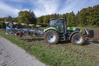 Farmer with tractor ploughing his field with a 5-turn rotary plough, Franconia, Bavaria, Germany,