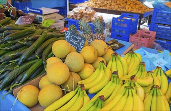 Market stall with a variety of fresh fruit such as bananas, melons and cucumbers. A colourful and