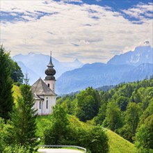 Maria Gern church in a picturesque mountain landscape, surrounded by dense green vegetation and