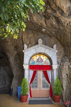 Sanctuary entrance in rock face, red curtains, religious icons, Church of Mary the Fountain of