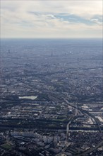 Expansive city view from the air with prominent tower and light cloud cover, flight, aerial view