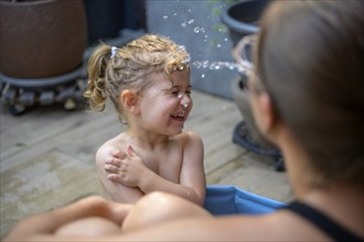 A child laughs and plays in the water on a warm summer's day