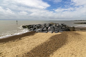 Rock armour groynes on beach managing longshore drift, Felixstowe, Suffolk, England, UK