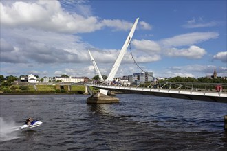 A jet ski passes under a striking bridge surrounded by calm waters, Londonderry