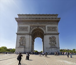 Front view of the Arc de Triomphe, people walking under the sunny sky, Paris