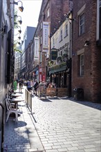 Lively pedestrianised area with shops and people walking along a brick street, Liverpool