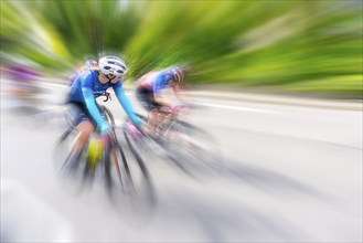 Two female cyclists in sportswear and helmets riding at high speed on a road, racing, the blur of