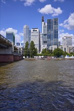 Skyscrapers and Untermainbrücke with Main river under blue sky with cumulus clouds in Frankfurt am