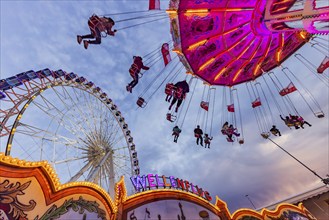 Chain carousel and Ferris wheel in the evening. 177th Cannstatter Volksfest at the Cannstatter