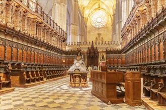 Cathedral nave with ornately decorated wooden seats and vaulted ceiling, Seville