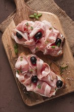 Breakfast, bacon and olives sandwich, on a cutting board, top view, close-up, no people