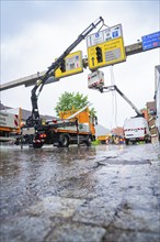 Two cranes working on display boards on wet ground in the rain, Hermann Hesse railway construction