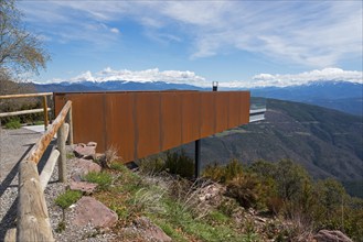 Aussichtsplattform aus rostfarbenem Metall und Holzgeländer mit weiten Blick auf die Berge und den