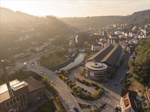 An urban environment with numerous buildings and streets along a river, surrounded by hills taken