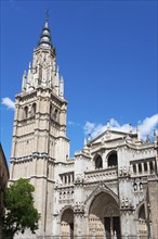 Gothic cathedral with impressive bell tower and detailed architecture against a blue sky,