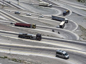 Heavy traffic of trucks on mountain pass Los Caracoles, The Snails, road connecting Chile and