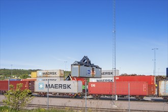 Loading of freight container with a crane on railway wagon at an industrial area, Sweden, Europe