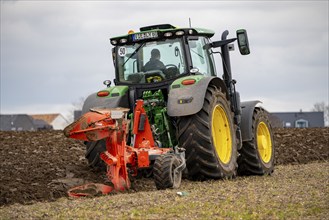 Tractor with a plough preparing the soil of a field for planting, Agriculture, Spring