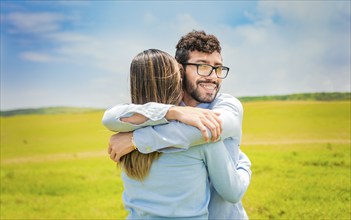 A man hugging his woman in a beautiful field, Close up of a happy couple hugging in the field, a