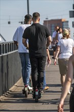 Pedestrians and e-scooters on a pavement, getting close and in each other's way, illegal driving on