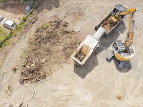 Aerial view of an excavator working near wood waste on a construction site, demolition site,