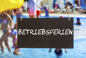 Symbolic image of company holidays: Sign with the inscription BETRIEBSFERIEN in front of summer