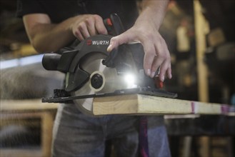 A man cuts wood with a hand-held circular saw. Berlin, 14.08.2024