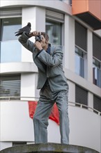 Real crow on a pillar saint, The Photographer, in front of the main railway station in Düsseldorf,