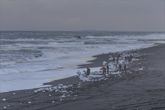 Tourists photographing ice floes on the beach, waves, sea, clouds, winter, Diamond Beach,